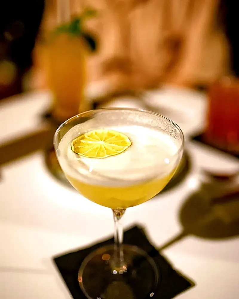 Un cocktail servi en coupe, mousse légère et rondelle de citron vert