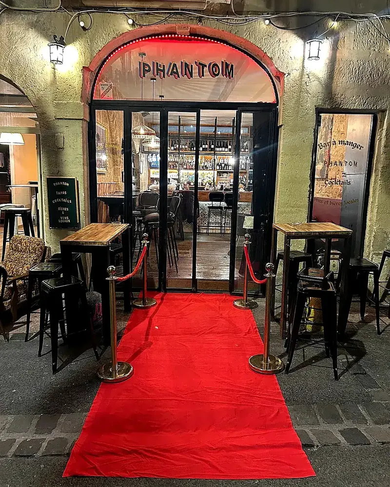 L'entrée du Phantom le soir : tapis rouge, enseigne et mange-debout en terrasse
